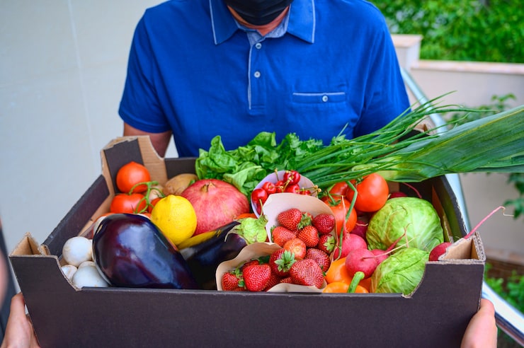 delivery-man-wearing-face-mask-holding-box-with-vegetables_1268-14612